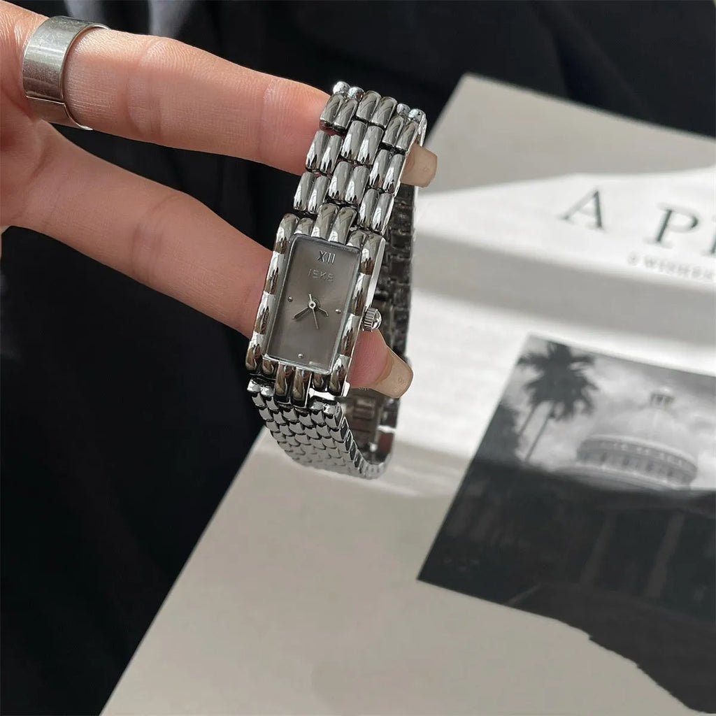 Women's silver and gold bracelet-style watch with a small white dial and butterfly buckle.