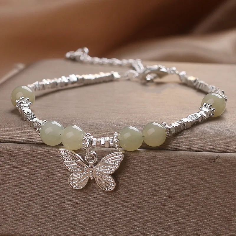 Hetian jade beads bracelet with silver butterfly pendant on a white background