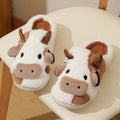 White women's cow pattern slippers made of soft faux fur with textured anti-slip soles.