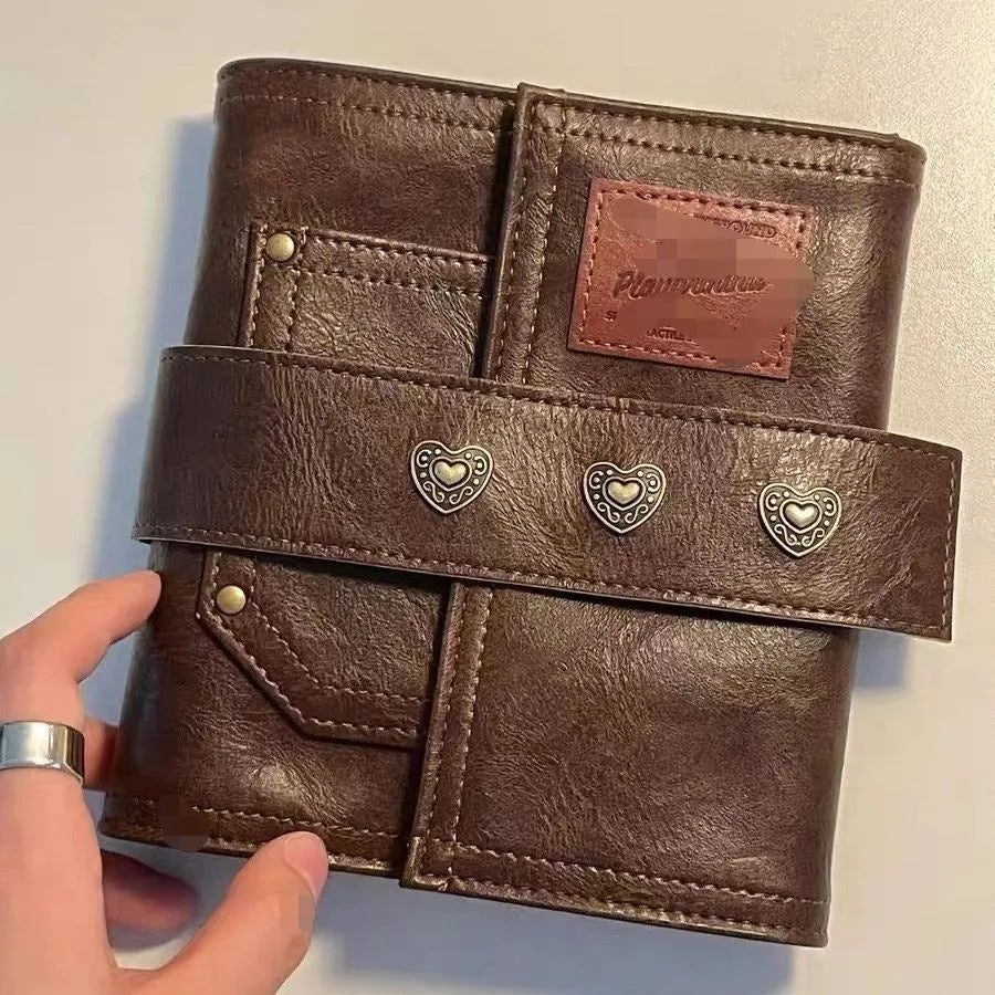Brown A7 retro notebook with buckle closure showing loose-leaf binding and raw wood pulp paper