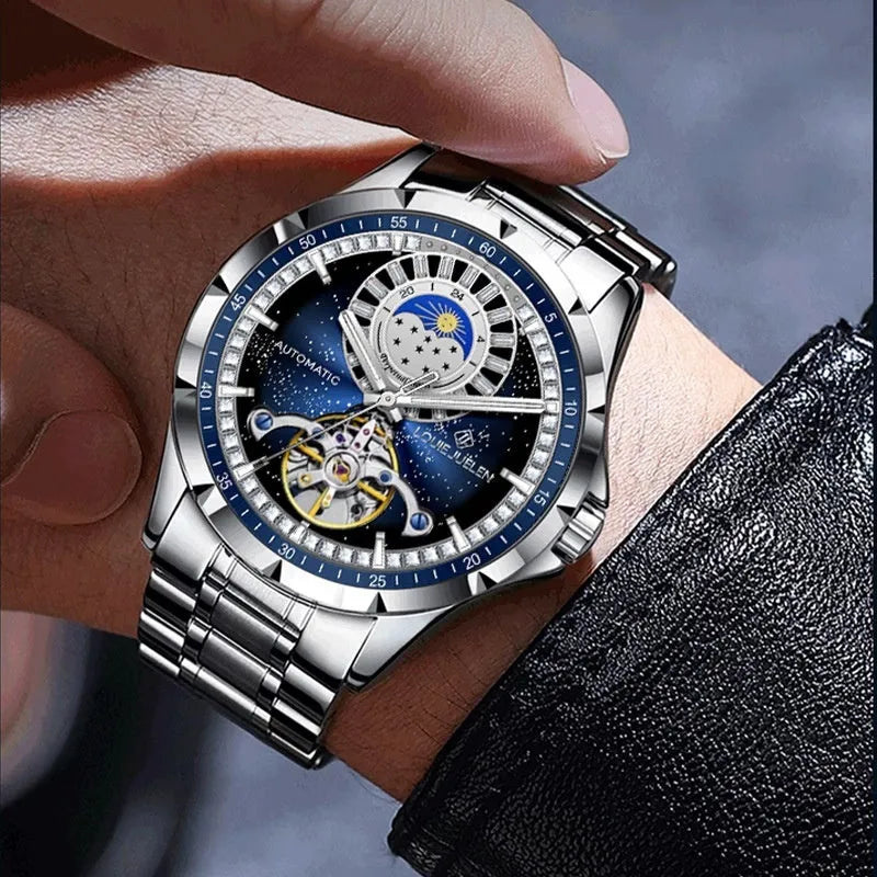 Men's silver automatic mechanical watch with blue dial and stainless steel bracelet on wrist.