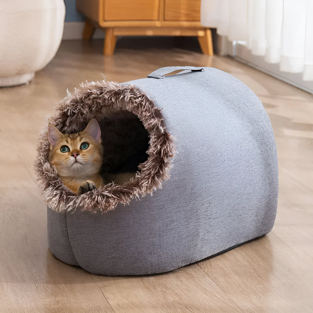 Grey fleece-lined closed cat sleeping bag with portable handle on brown floor