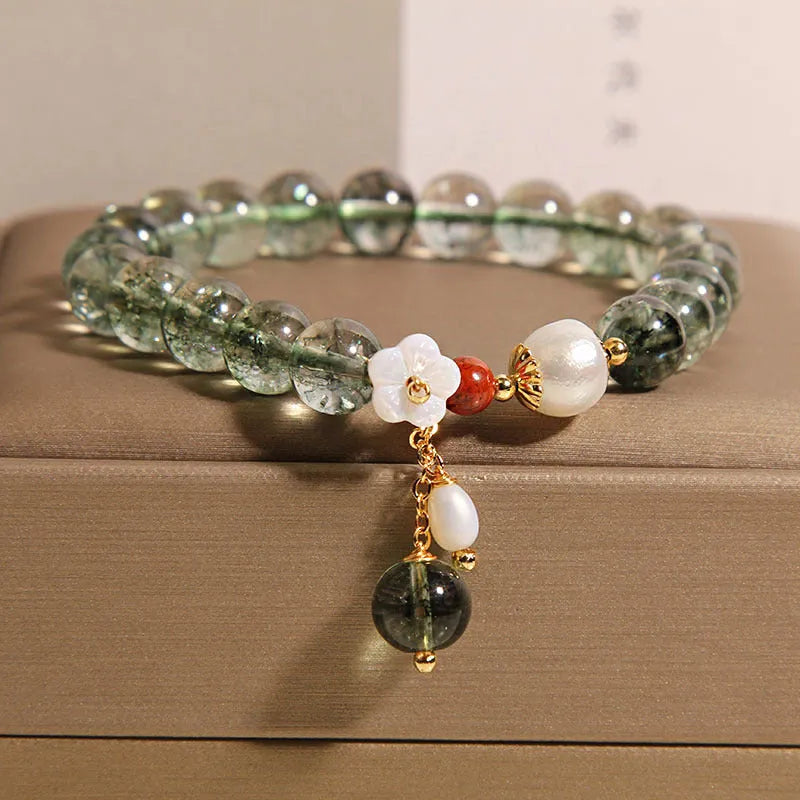Green phantom quartz crystal bracelet with shell flower charm on a woman's wrist