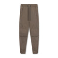 Man wearing loose grey running trousers with tied ankles, made from quick-dry polyester fabric.