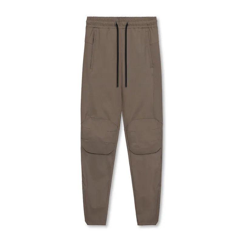 Man wearing loose grey running trousers with tied ankles, made from quick-dry polyester fabric.