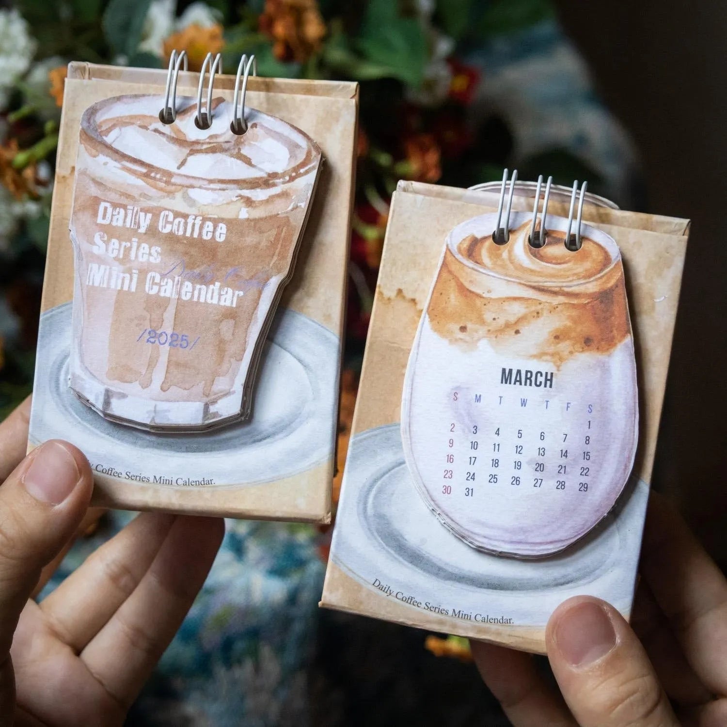 Small 2025 mini desk calendar open to a daily page, showing modern simple design on a desk.