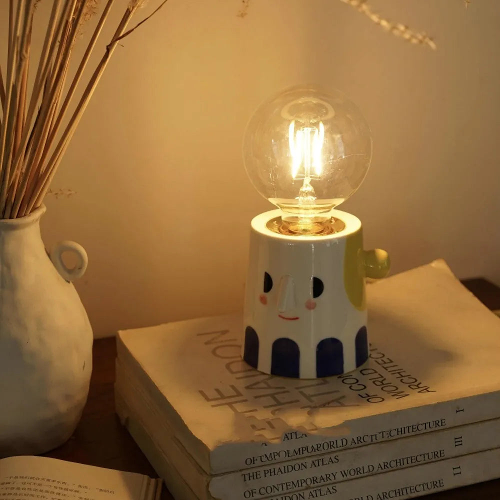Handmade white ceramic table lamp with a creative ball headlight design on a wooden surface.