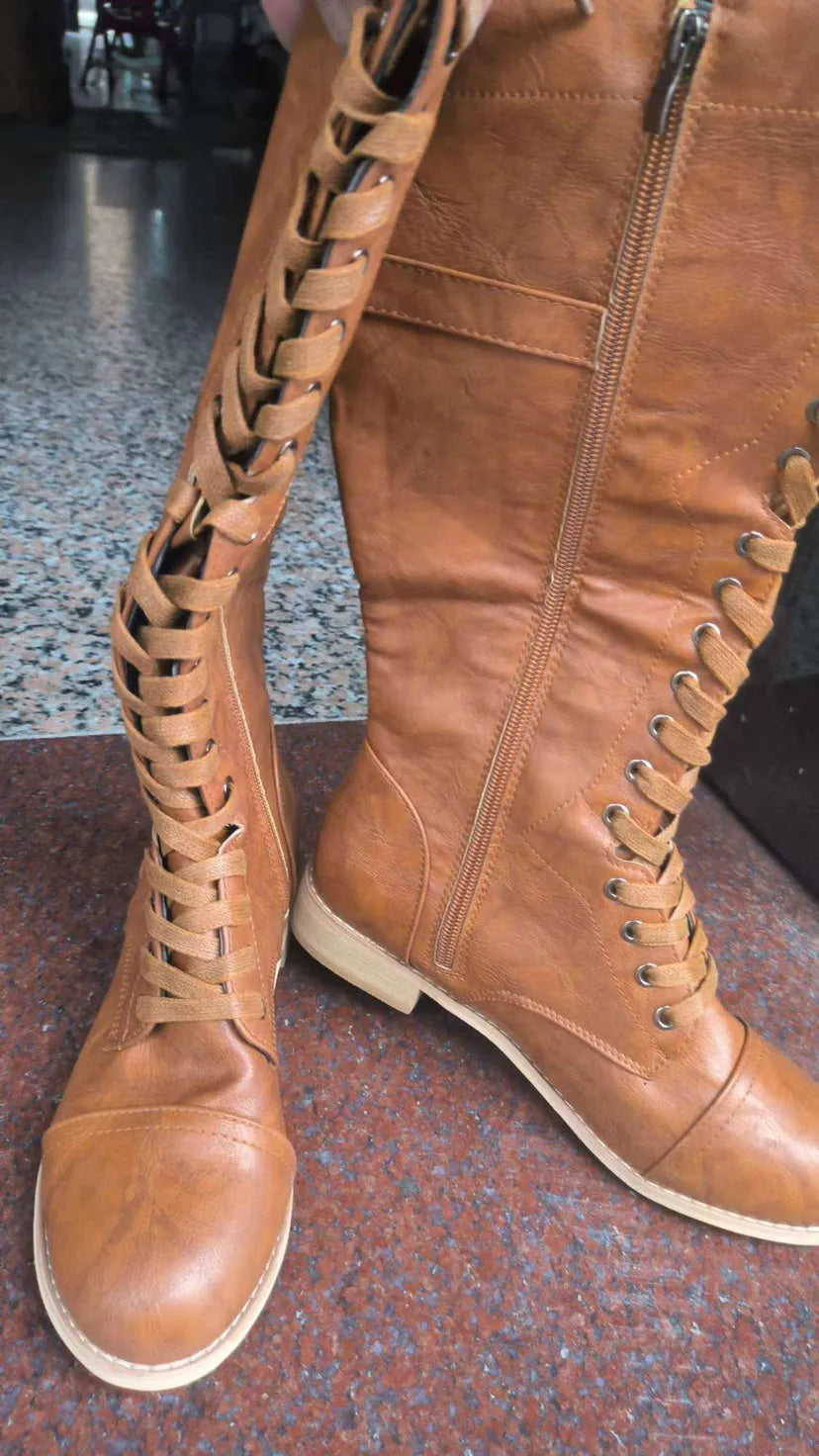Women's black cross strap knight boots made from artificial PU, showing the strap detail and ankle height