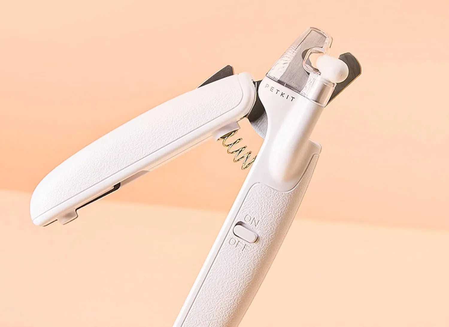 White pet nail clipper with LED light and transparent anti-splash guard on a blue background.