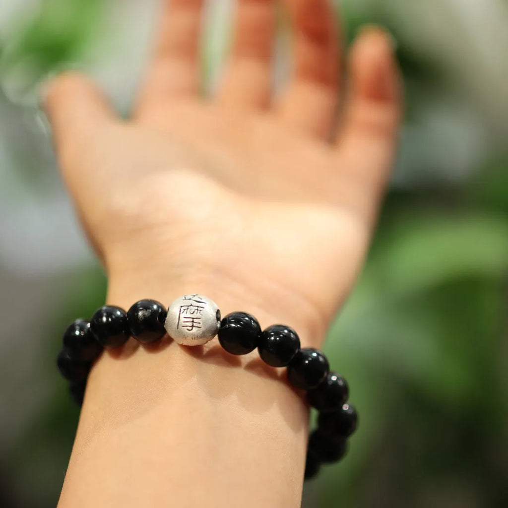 Close-up of a women's black agate bracelet with a sterling silver clasp on an alloy chain.