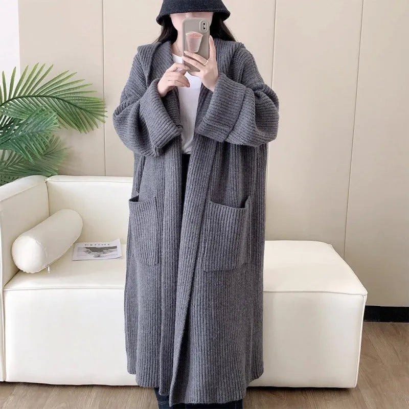 Loose grey hooded cardigan coat for women with long sleeves on a hanger.