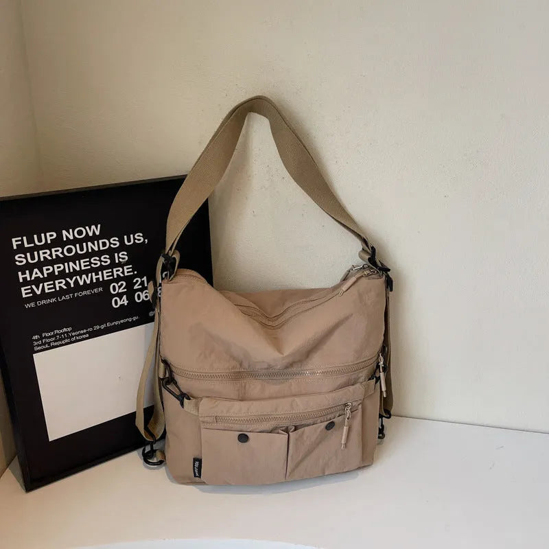 A square-shaped nylon crossbody bag for women in a choice of colours, showing shoulder straps and external pocket.