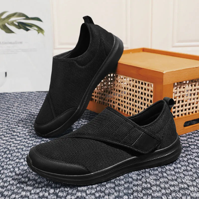 A pair of grey mesh walking shoes with a Velcro strap closure, shown on a white background.