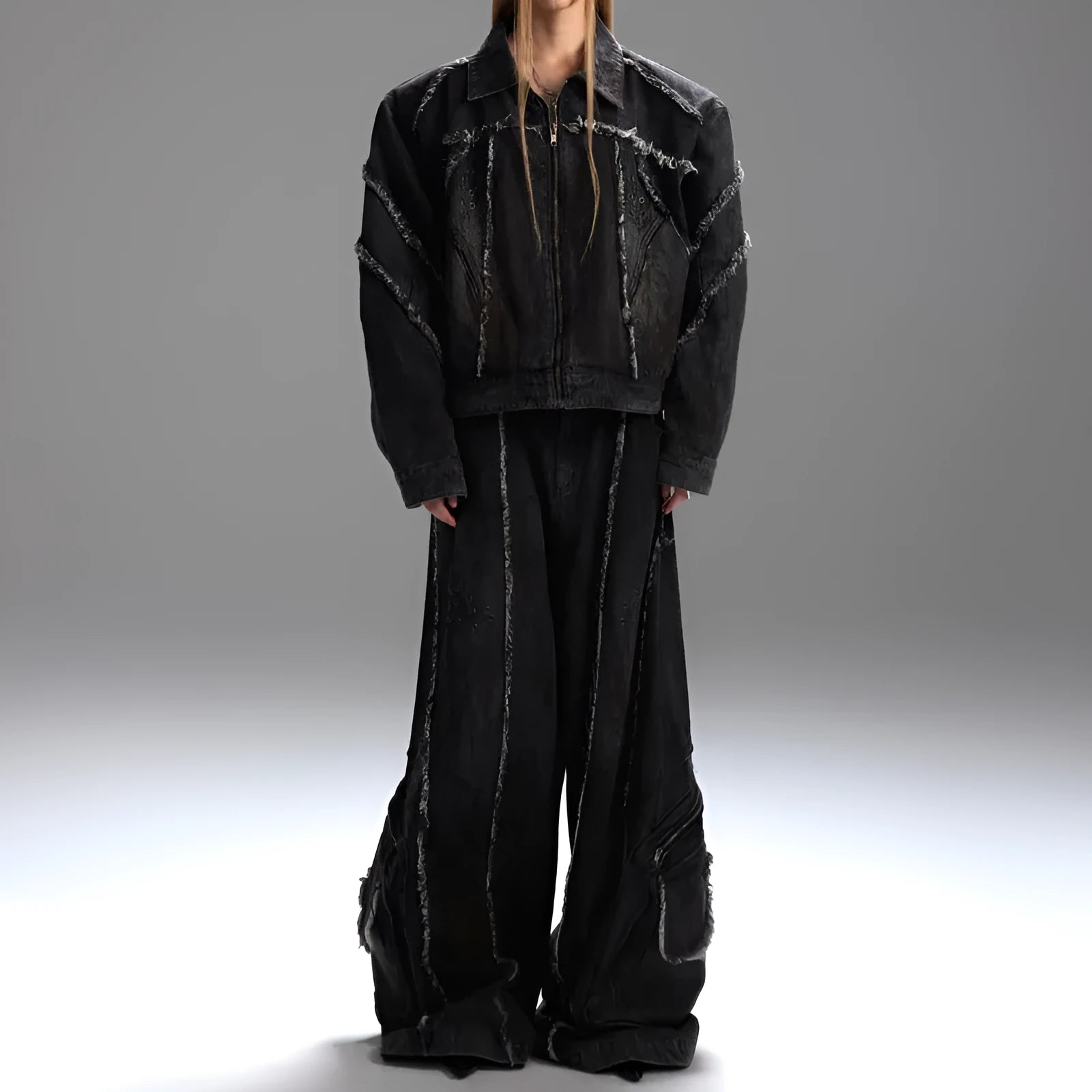 Black distressed raw-edge denim coat with padded shoulders and splash-dye gradient, paired with matching black pants.