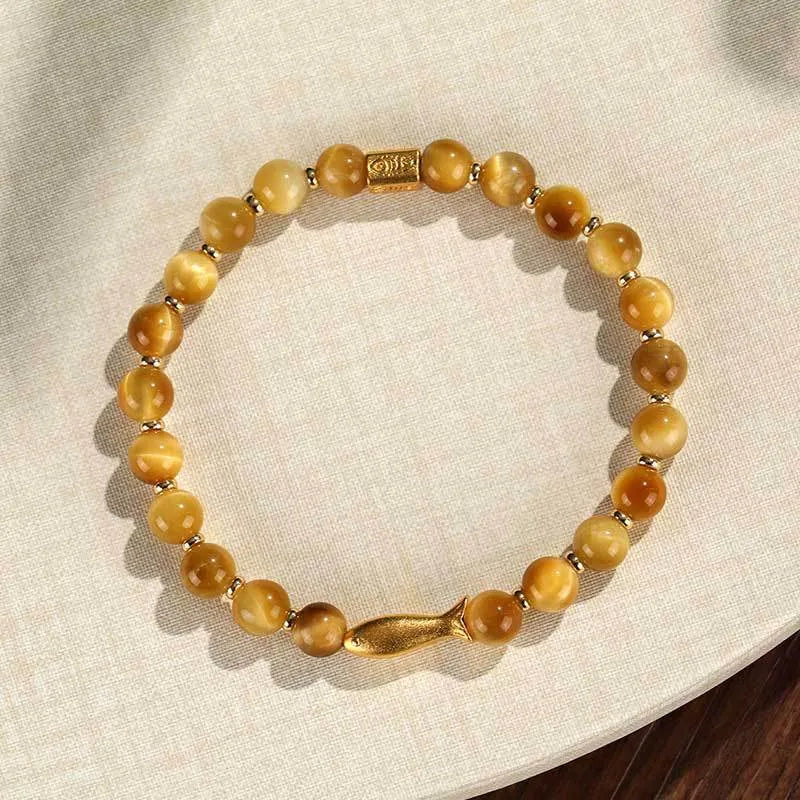 Close-up of a women's bracelet with small fish-shaped Tiger Eye stone beads in yellow, red, or gold colours.