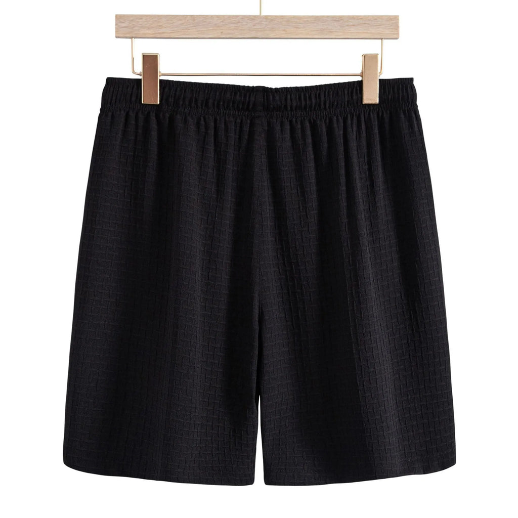 Men's black cotton blend short sleeve shirt and shorts beach suit laid flat.