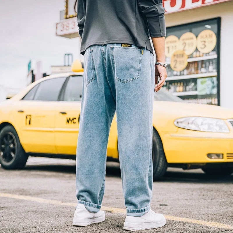 Men's dark blue loose straight-leg casual jeans on a hanger, showing mid-waist and zipper fly.