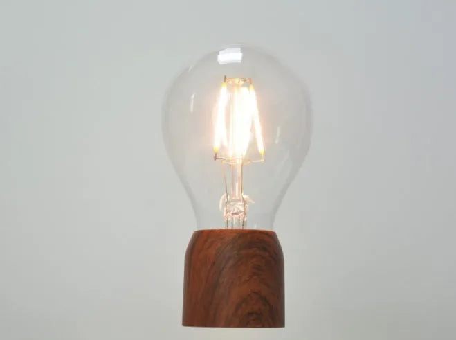 Magnetic levitation desk lamp with floating light bulb on imitation wood base.
