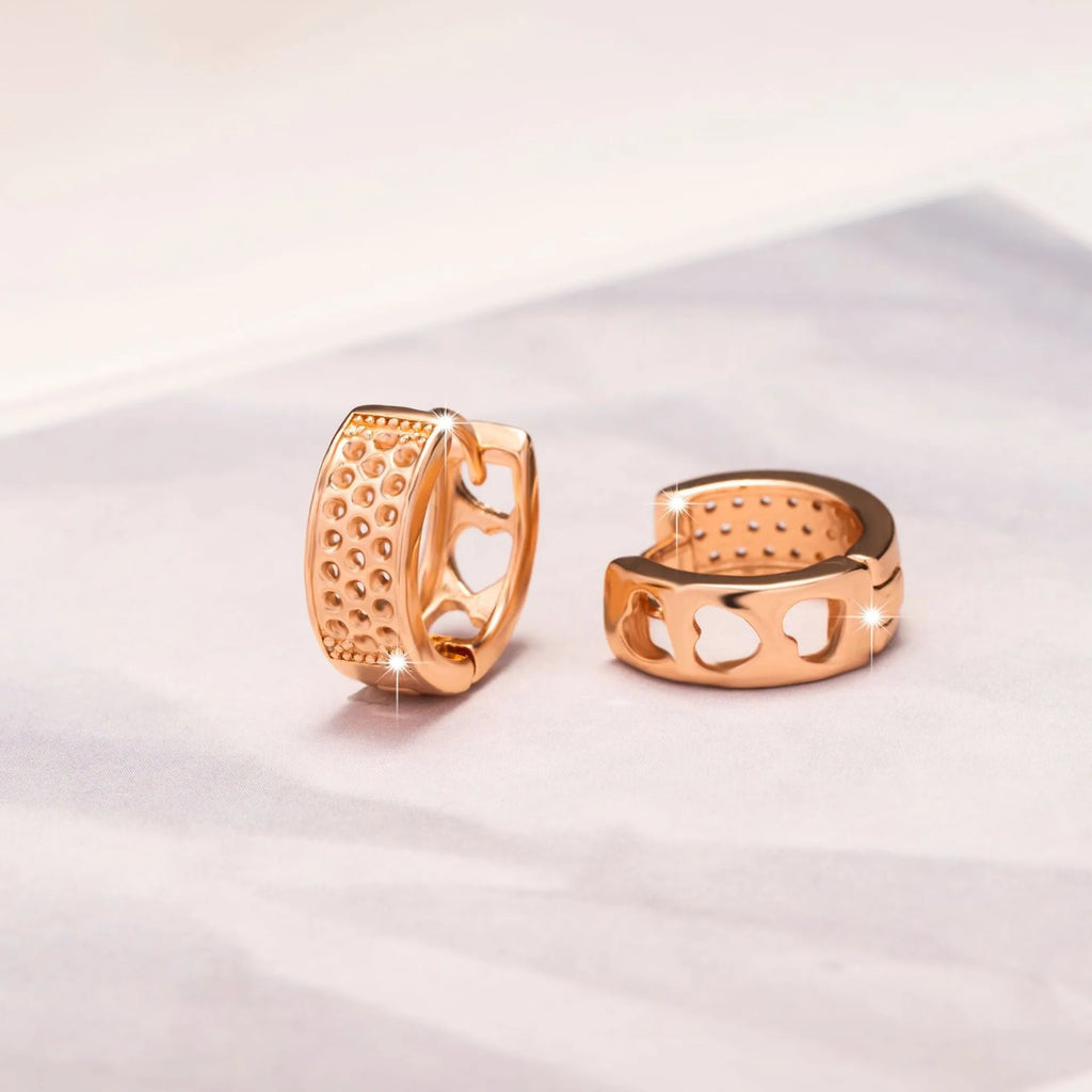 Rose gold circular earrings with three hollowed-out heart shapes.