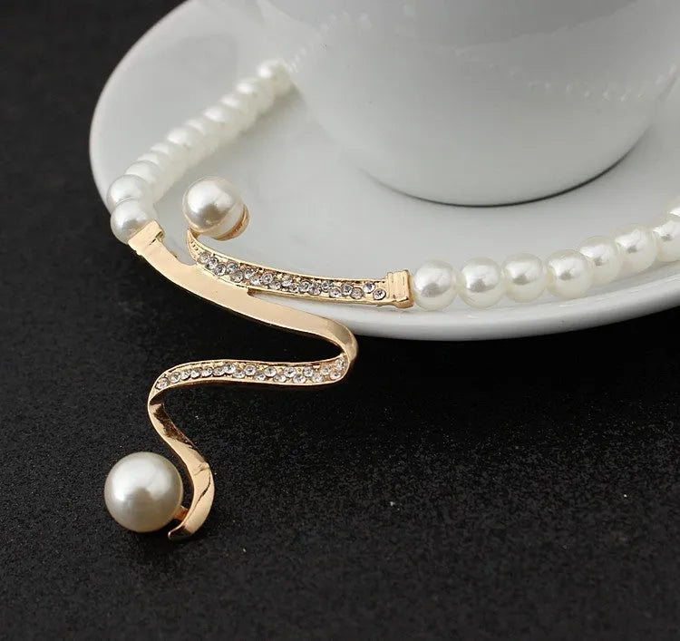 Gold electroplated pearl necklace and drop-shape earrings set on a jewellery display.