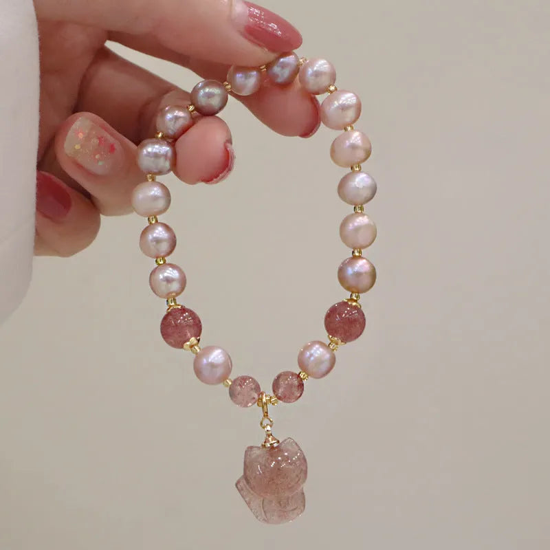 Light pink women's bracelet with freshwater pearls, strawberry quartz beads, and a silver fox charm on a white background.