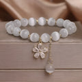 White cat's eye stone women's bracelet with a safety buckle and small flower tassel.