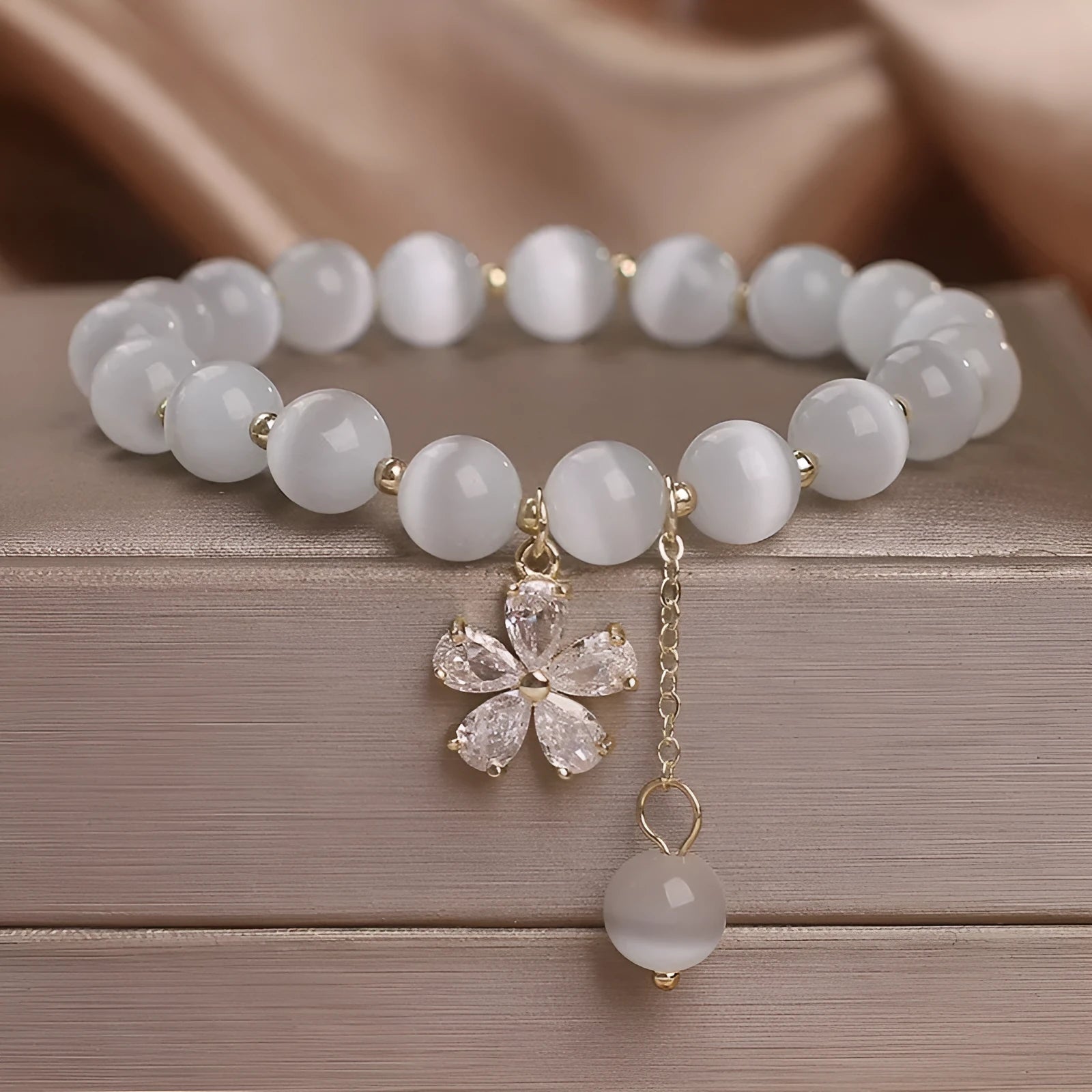 White cat's eye stone women's bracelet with a safety buckle and small flower tassel.