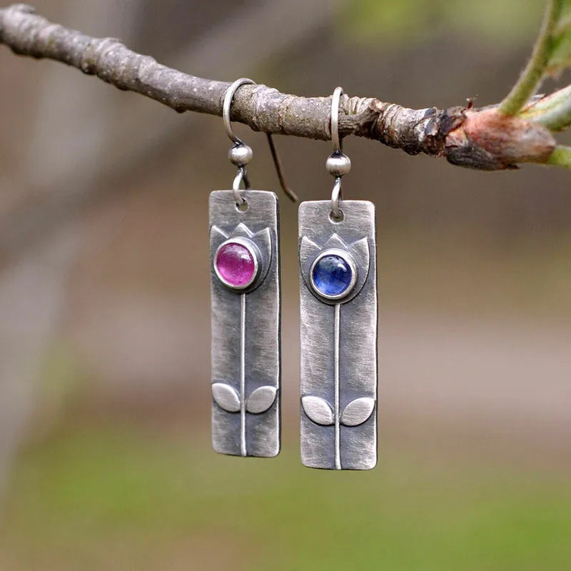 Antique finish metal stud earrings with a red sapphire in an ellipse shape, retro style.
