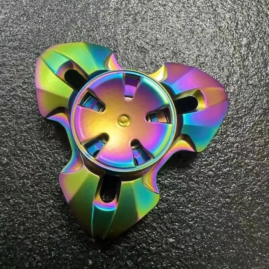 Alloy metal fingertip gyro decompression toy in gun metal colour, spinning on a surface.