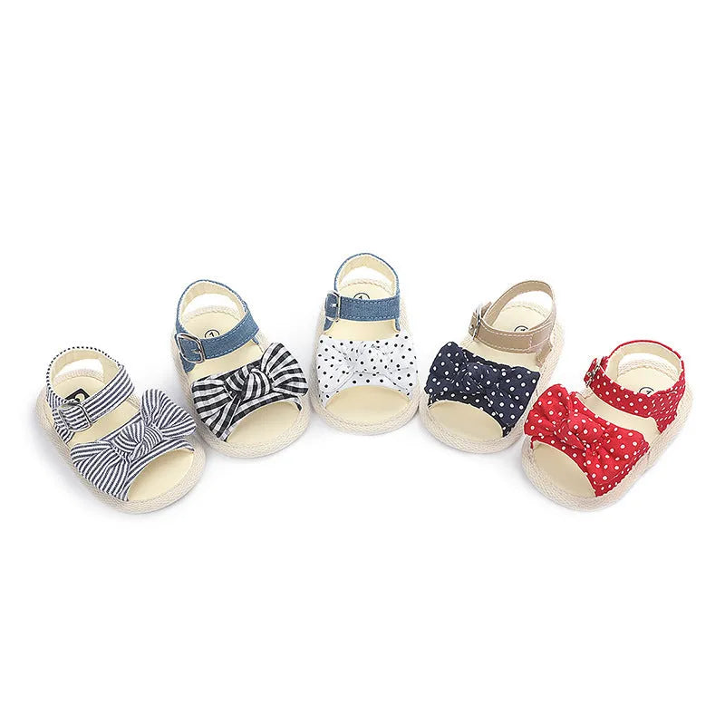 White and black Velcro baby shoes for toddlers, showing low-cut design and strap detail.