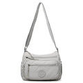 Grey water-repellent nylon crossbody bag showing front three-dimensional pocket and adjustable shoulder strap.