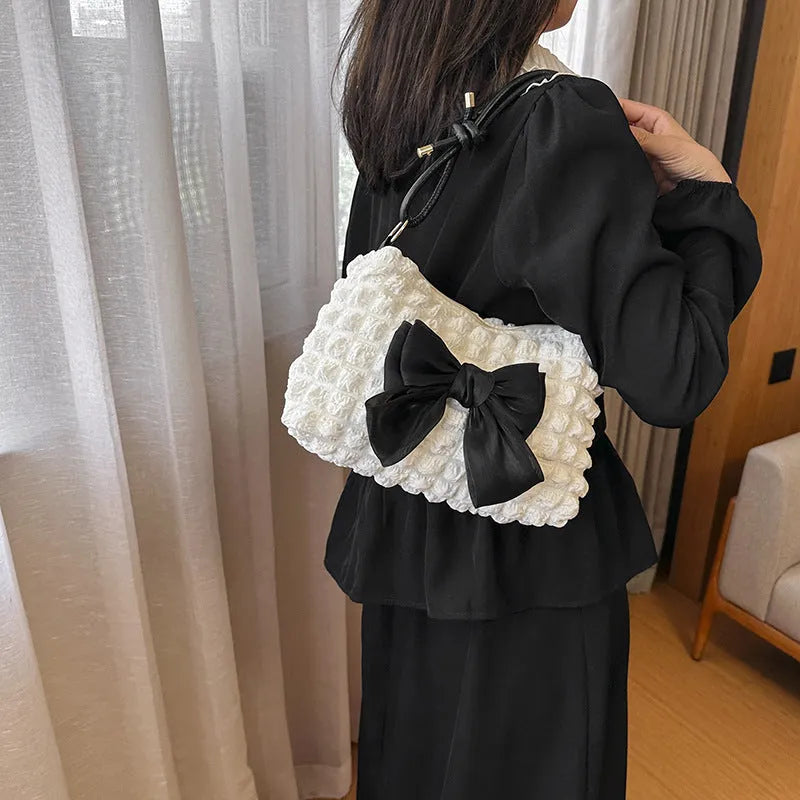 Street style canvas one-shoulder handbag in horizontal square shape with visible stitching.