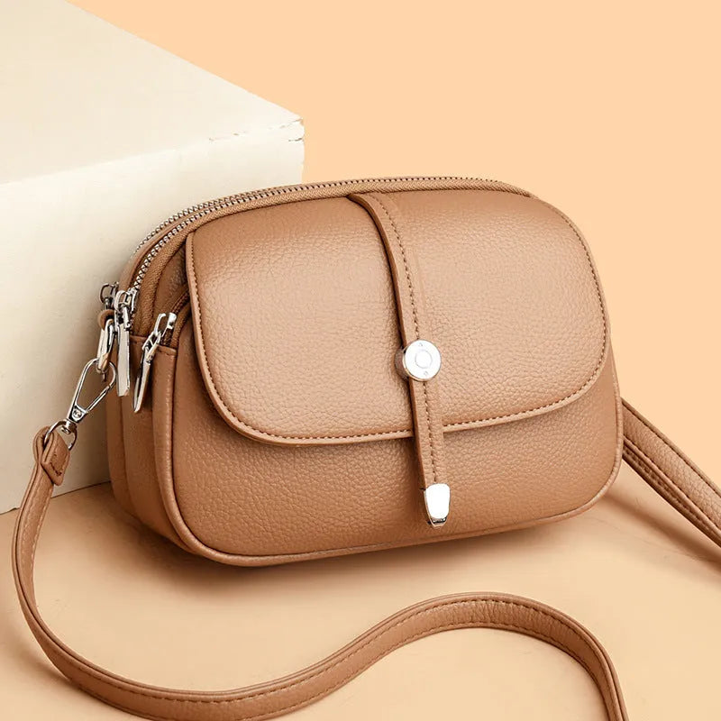 Women's oval crossbody shoulder bag in black, khaki or dark brown with visible sewing thread detail