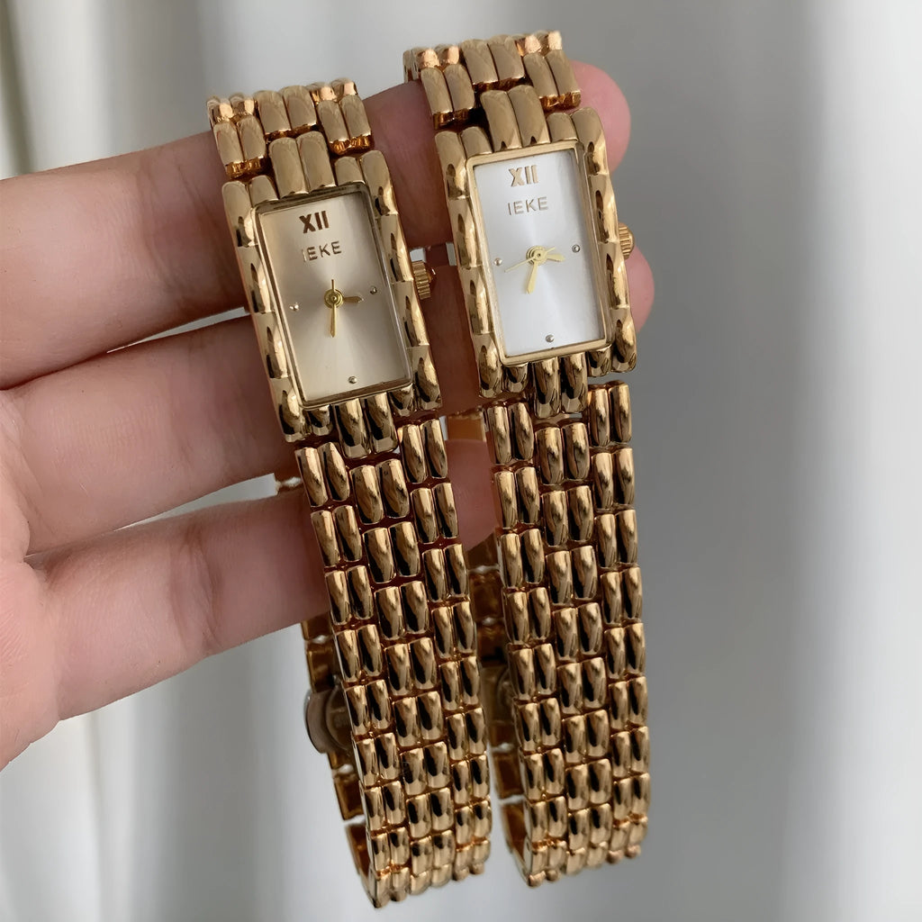 Women's silver and gold bracelet-style watch with a small white dial and butterfly buckle.