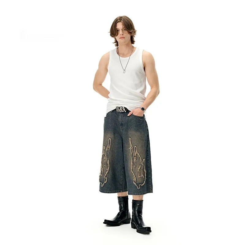 Men's black cropped denim shorts with orange flame embroidery patch on leg
