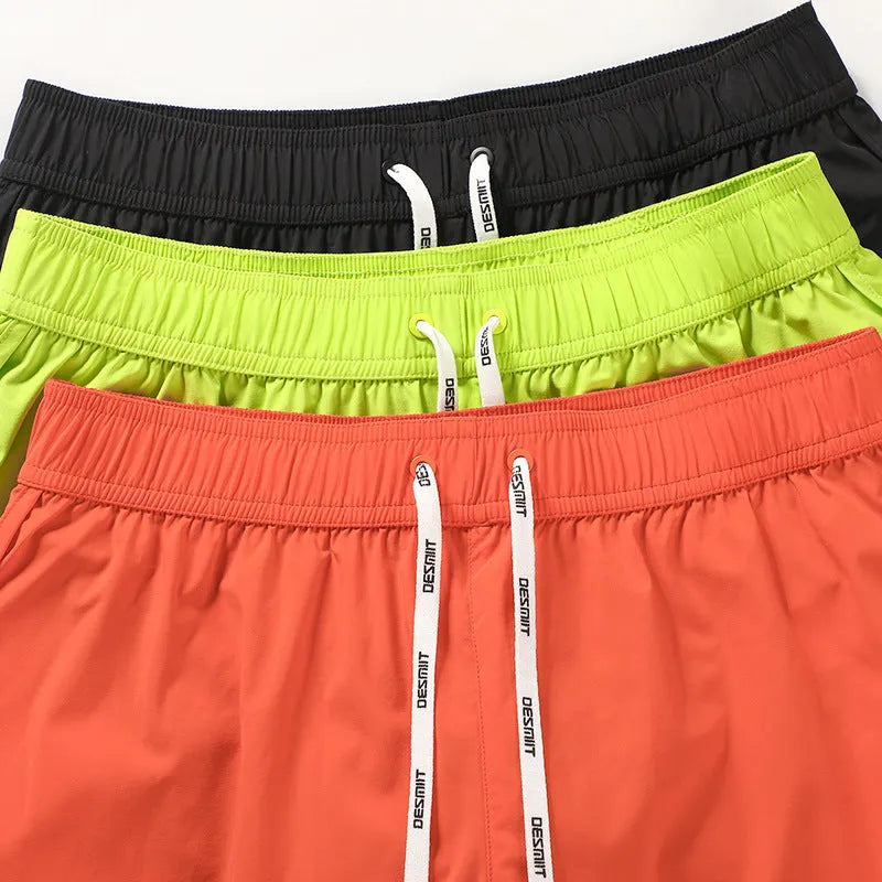 Men's loose polyester surfing shorts in orange, fluorescent green, or black on a size chart.