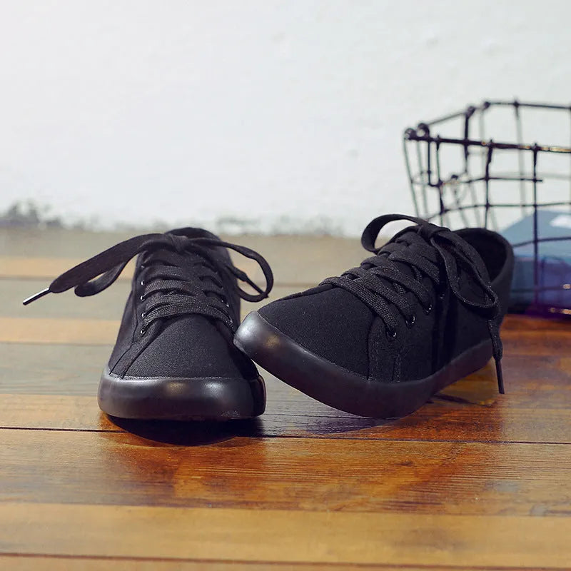 All black women's canvas lace-up work shoes with flat rubber soles.