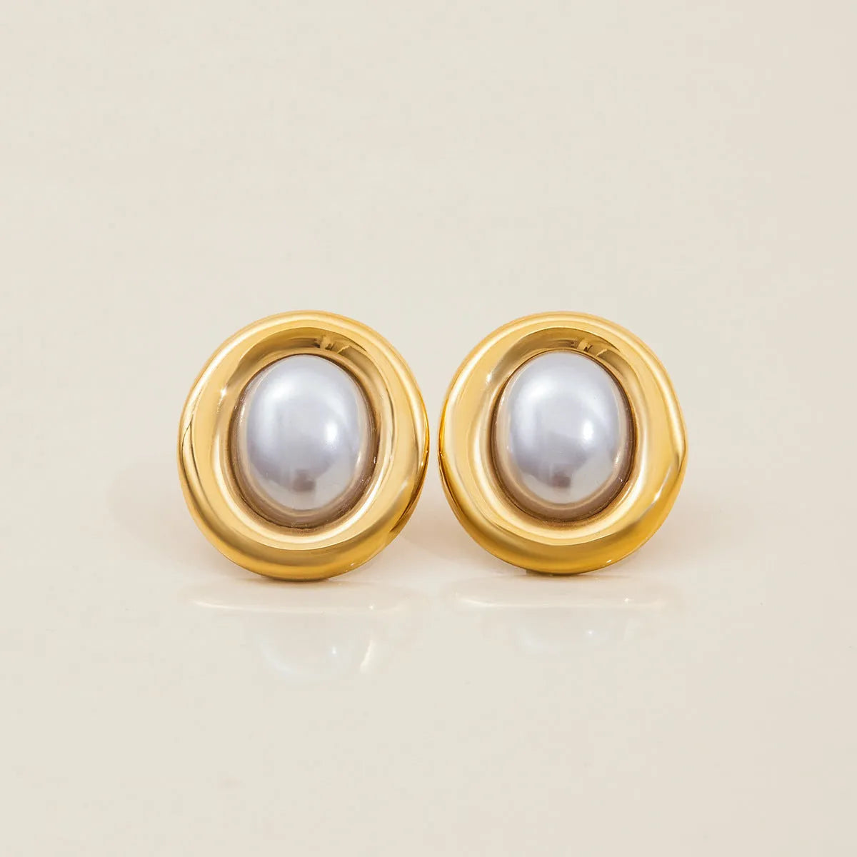 Close-up of a pair of women's stainless steel vintage pearl ear studs with a silver-toned post on a white background.
