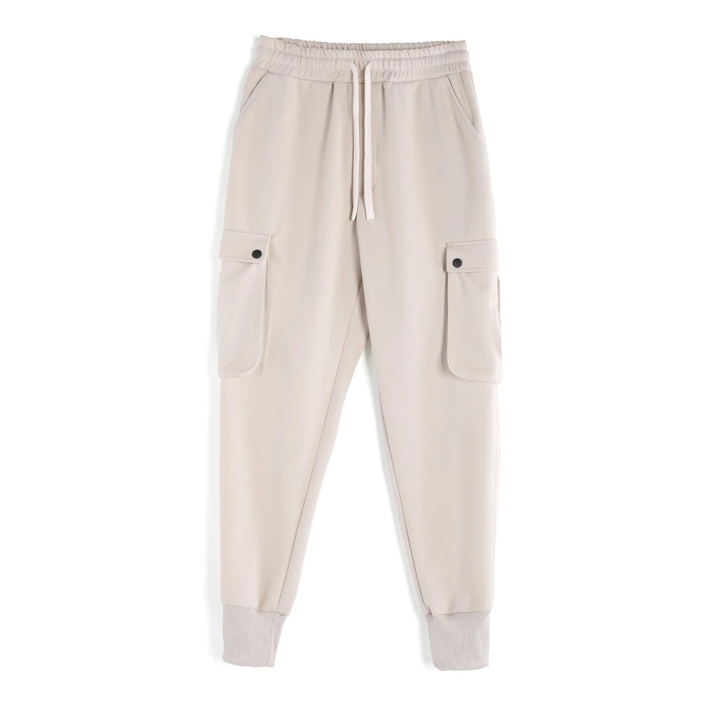 Men's loose light grey cotton trousers with ankle ties and multiple pockets laid flat.