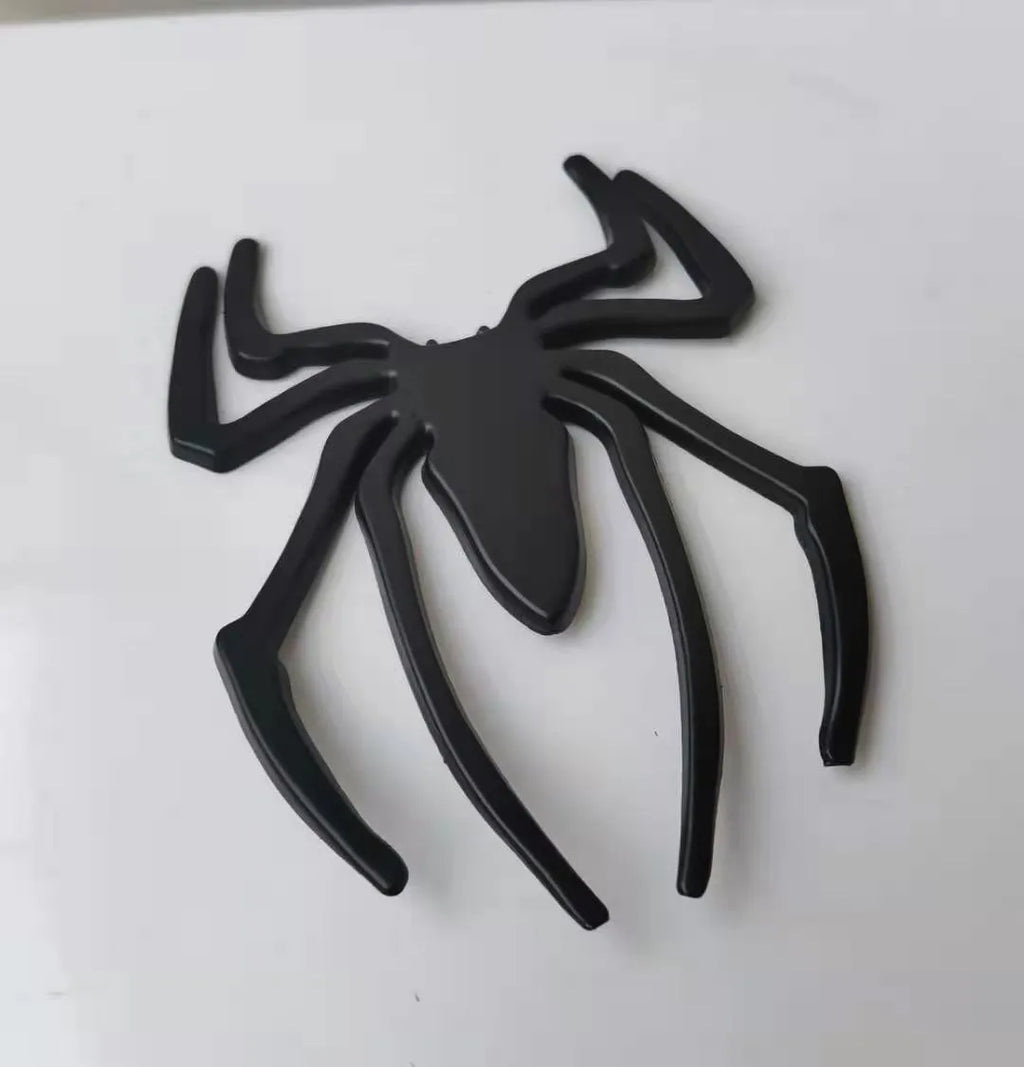 Three-dimensional metal spider bumper sticker in metallic finish measuring 7cm by 5cm