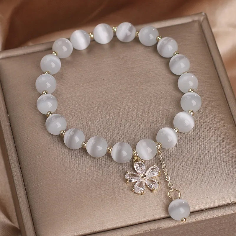 White cat's eye stone women's bracelet with a safety buckle and small flower tassel.
