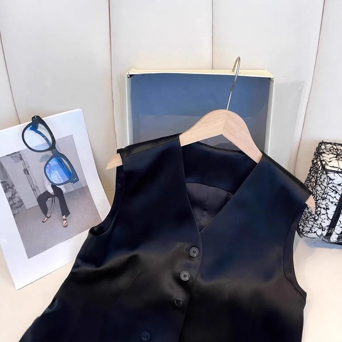 Black satin ladies sleeveless vest with V-neck and loose fit on a hanger.