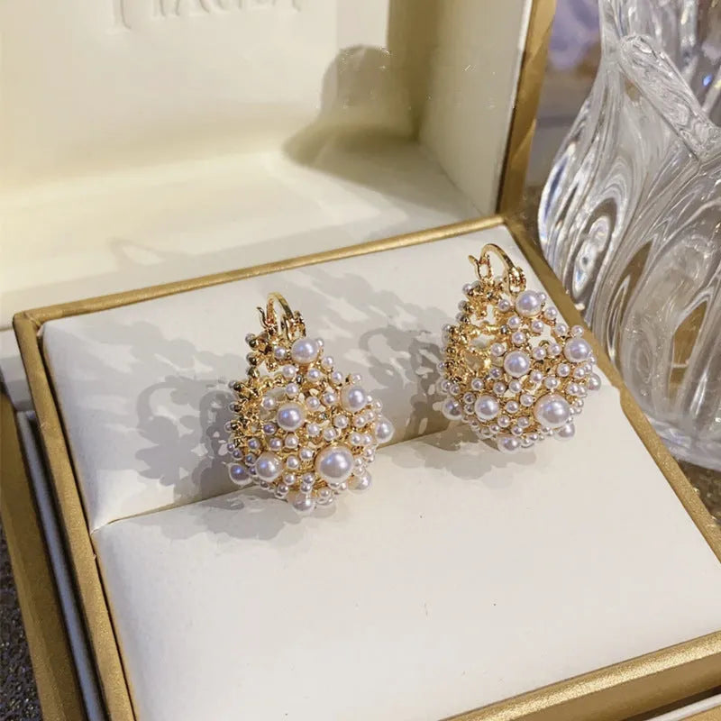 Gold-coloured copper flower basket earrings with small rice-shaped beads and pearl inlay detailing.