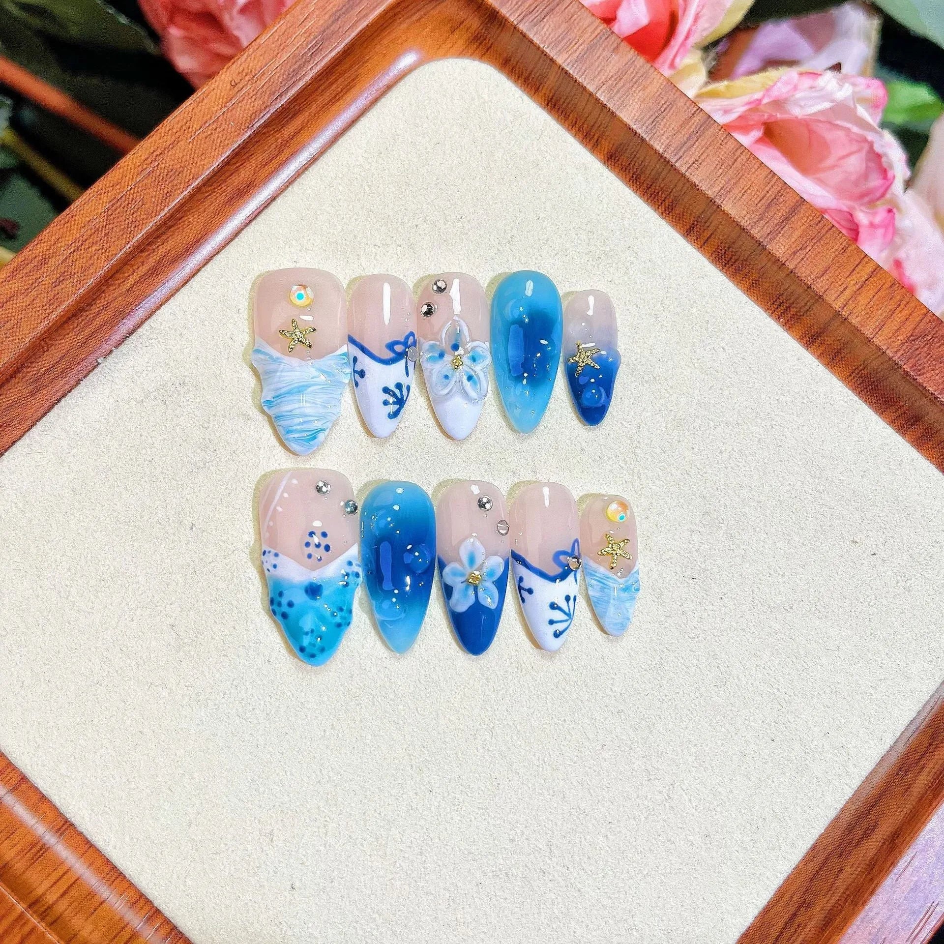 Set of blue hand-painted carved summer ice transparent plastic fake nails in XS, S, M, and L sizes.