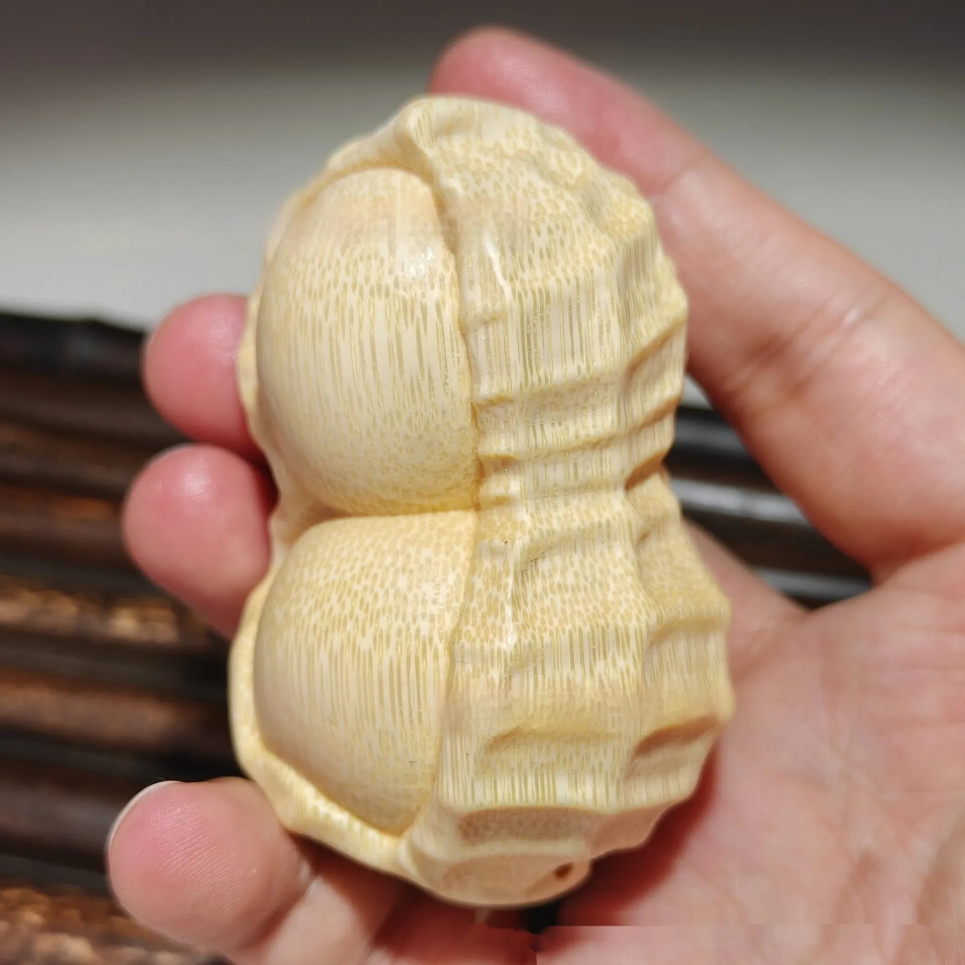 Solid natural bamboo carving of a peanut ornament on a wooden surface
