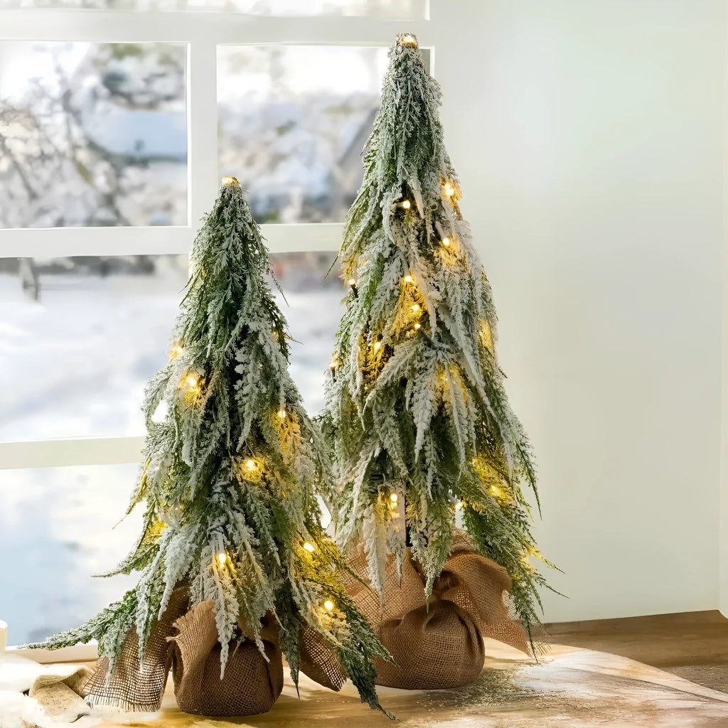 Small 24-inch frosted artificial Christmas tree with LED lights on a desktop.