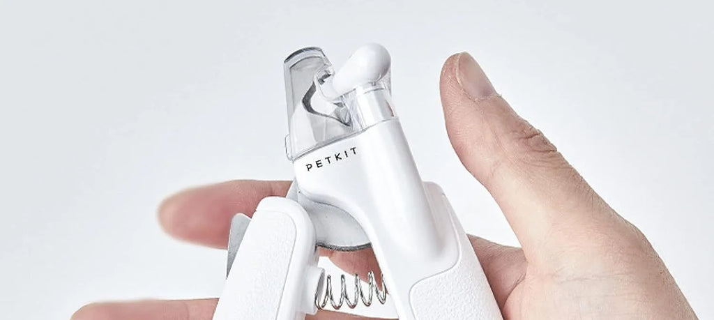 White pet nail clipper with LED light and transparent anti-splash guard on a blue background.