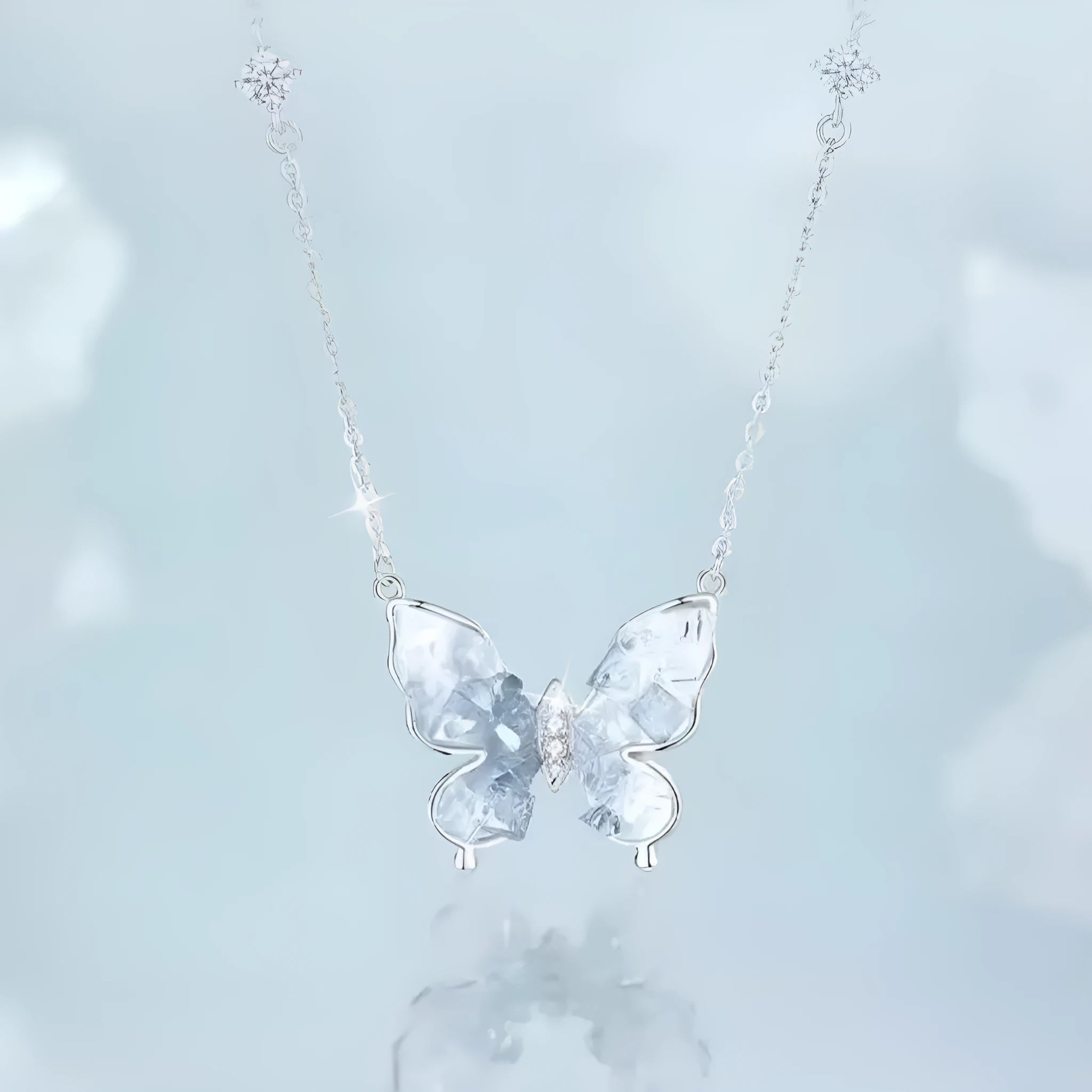 Close-up of a silver necklace with a detailed ice rain butterfly pendant on an O-ring chain.