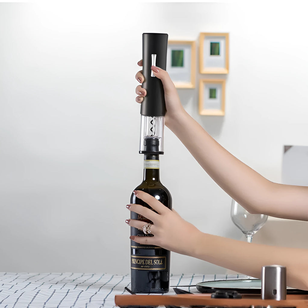Automatic electric wine opener with black ABS shell and foil cutter set on a table alongside a wine bottle