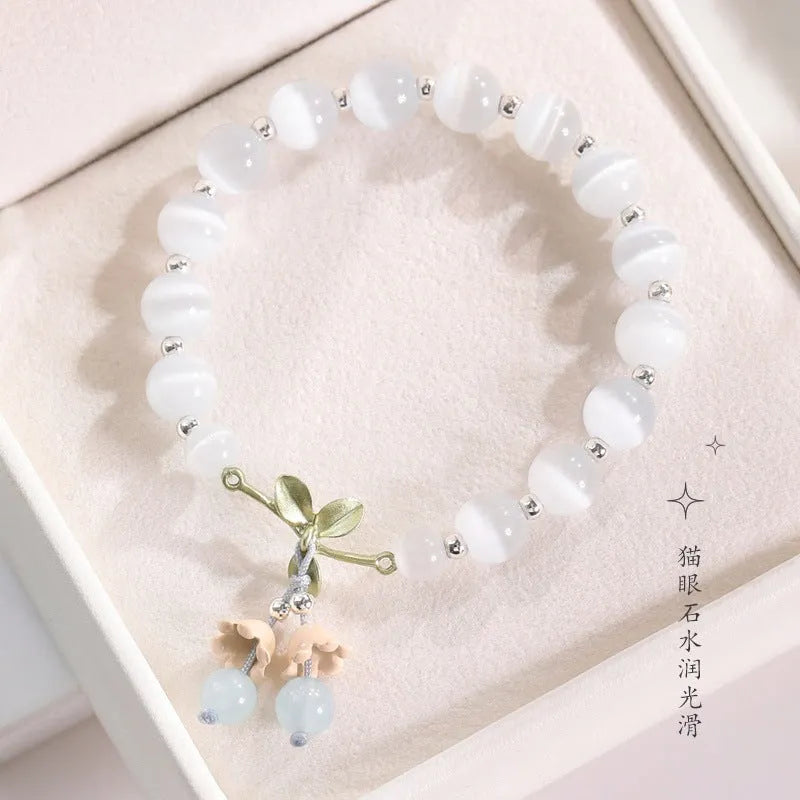 Close-up of a women's opal beaded bracelet with diamond-shaped cat's eye stones on a wrist.